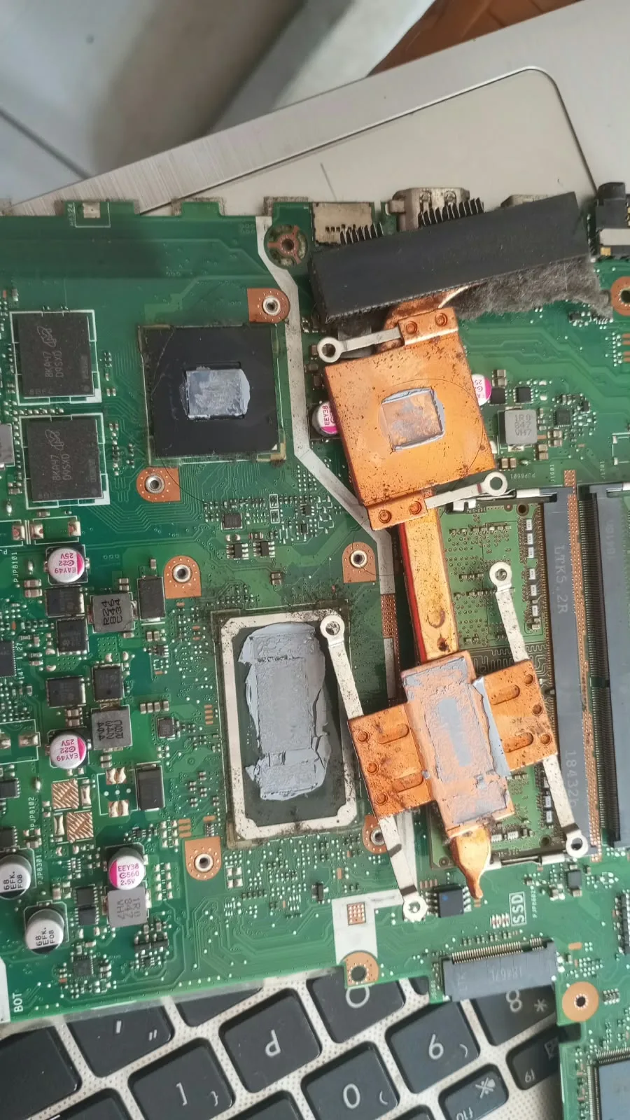 Dried thermal paste on the laptop's chips and heatsink before replacement